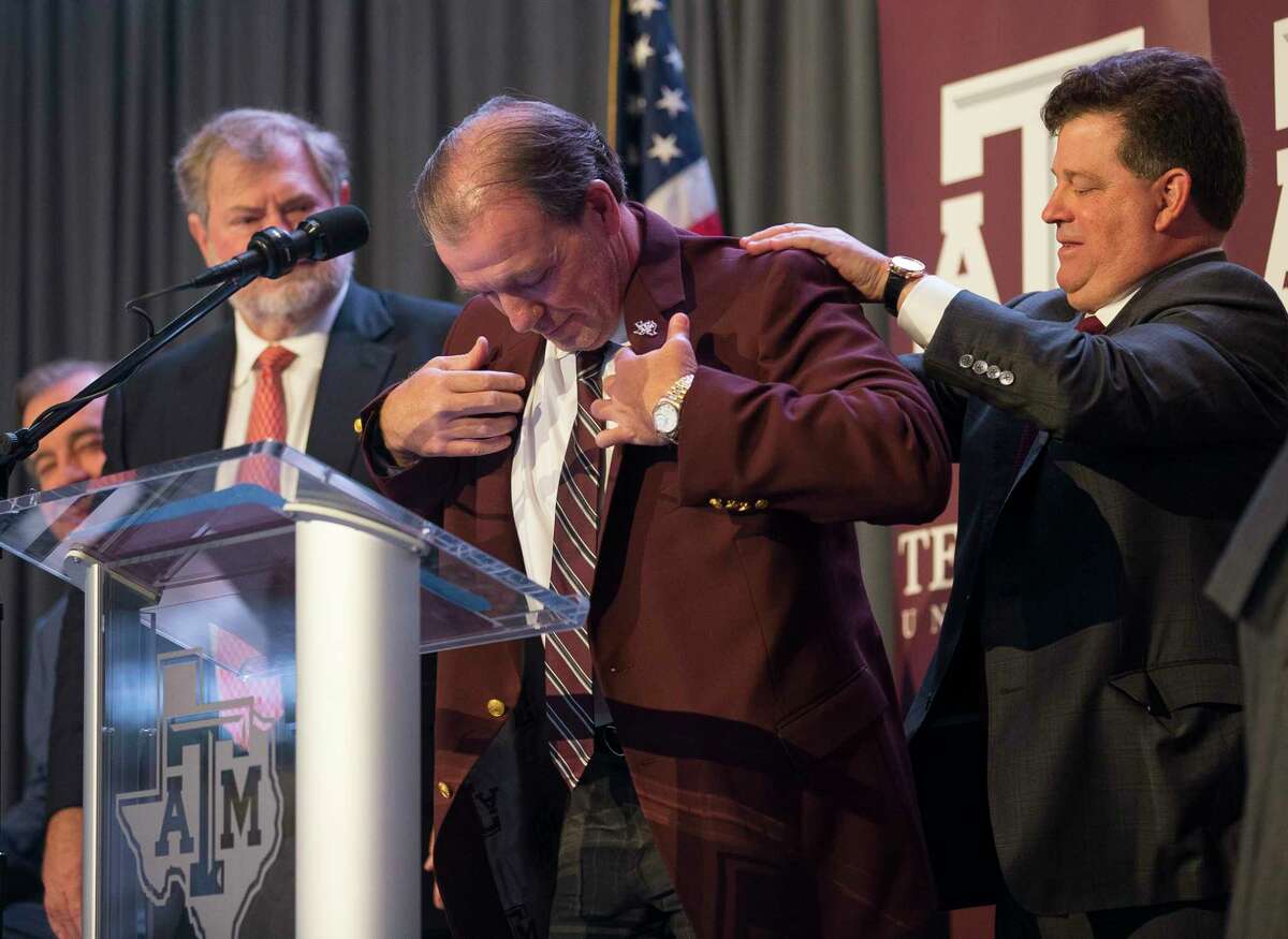 New Texas A&M University head football coach Jimbo Fisher is presented with a maroon jacket by athletic director Scott Woodward during a press conference at the school's Hall of Champions at Kyle Field, Monday, Dec. 4, 2017, in College Station.