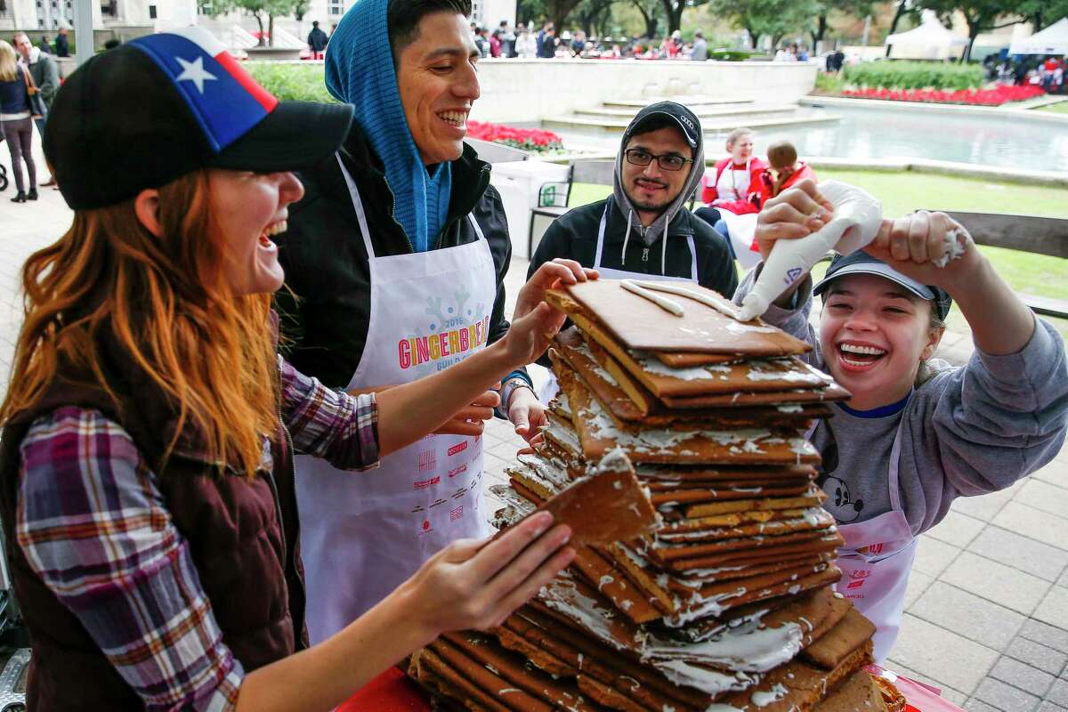 Morris Architects Emily Keller, left, and Irving Gomez, center, laugh as Mary Taylor Carwile, right, struggles to reach to the top of their christmas mountain to put on a layer of frosting as they compete to build the tallest gingerbread creation at the Gingerbread Build Off Dec. 10, 2016.
