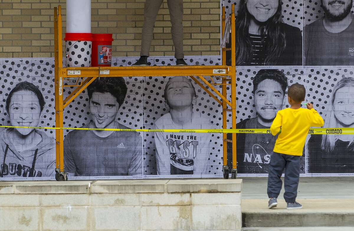Jaxon Ajoku, 3, whose mother is the director of the Center for Diversity and Inclusion at the University of Houston, plays in front of the posters being pasted on a wall outside the student center of people that were just photographed by the Inside Out Project's mobile photo booth truck at the University of Houston, Tuesday, Dec. 5, 2017, in Houston. The exhibit is intended to urge Congress to pass the DREAM act before the end of the year. ( Mark Mulligan / Houston Chronicle )
