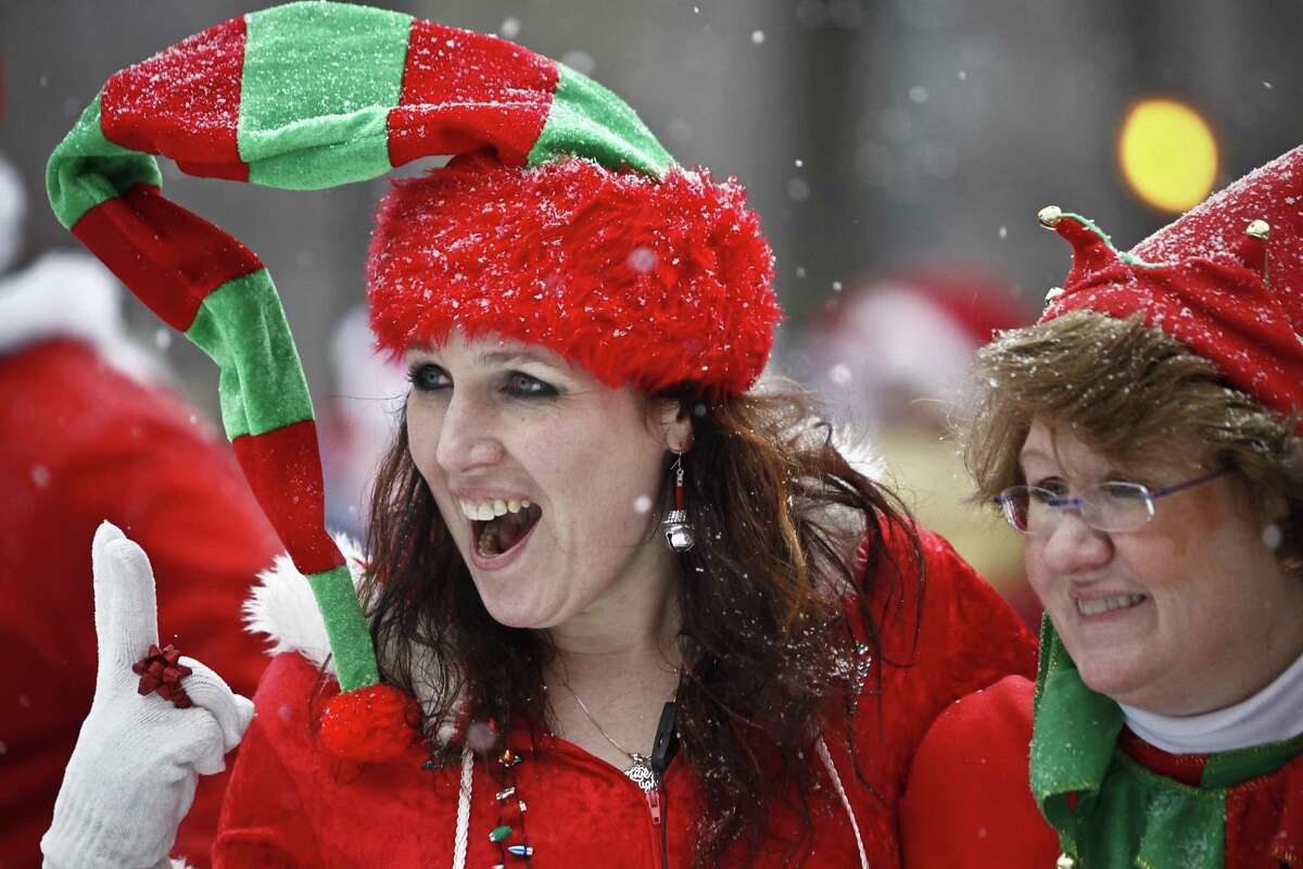Snow falls as revelers dressed as elves pose for a picture at Tompkins Square Park during the annual SantaCon bar crawl event on December 14, 2013 in New York City.