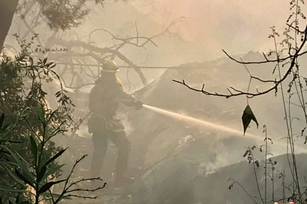 Los Angeles Fire Department firefighter hoses down hot spots in the backyard of a mansion on Moraga Drive in the the Bel-Air neighborhood of Los Angeles on Wednesday, Dec. 6, 2017.