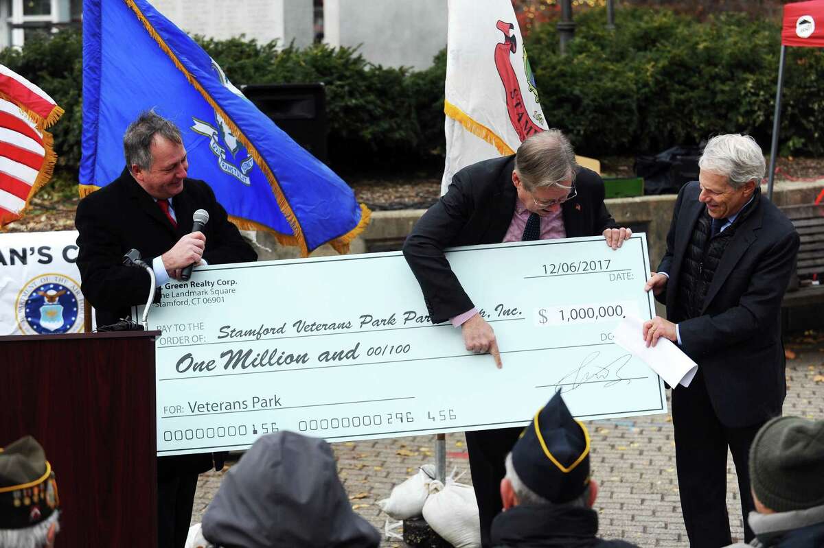 Stamford mayor David Martin points to the signature a large check presented to him by SL Green Realty senior VP Greg Caggainello, left, during press conference revealing advanced plans to renovate Veterans Park in downtown Stamford, Conn. on Wednesday, Dec. 6, 2017. The $1million check will be put towards the Veterans Park redesign efforts.