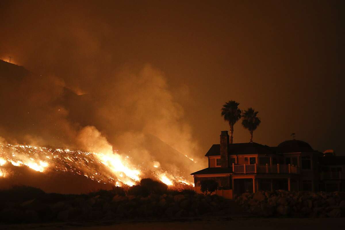 A wildfire threatens homes as it burns along the 101 Freeway Tuesday, Dec. 5, 2017, in Ventura, Calif. Raked by ferocious Santa Ana winds, explosive wildfires northwest of Los Angeles and in the city's foothills burned a psychiatric hospital and scores of homes and other structures Tuesday and forced the evacuation of tens of thousands of people. (AP Photo/Jae C. Hong)