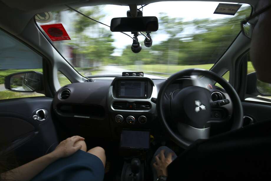 FILE: - In this file photo from Wednesday, Aug. 24, 2016, a driver, right, gets his hands off of the steering wheel of an autonomous vehicle during its test drive in Singapore. Autonomous vehicle software startup nuTonomy has made rides on its self-driving taxis available to the general public in Singapore for free, expanding a first-in-the world run that was initially invitation-only. (AP Photo/Yong Teck Lim, File) Photo: Yong Teck Lim, AP
