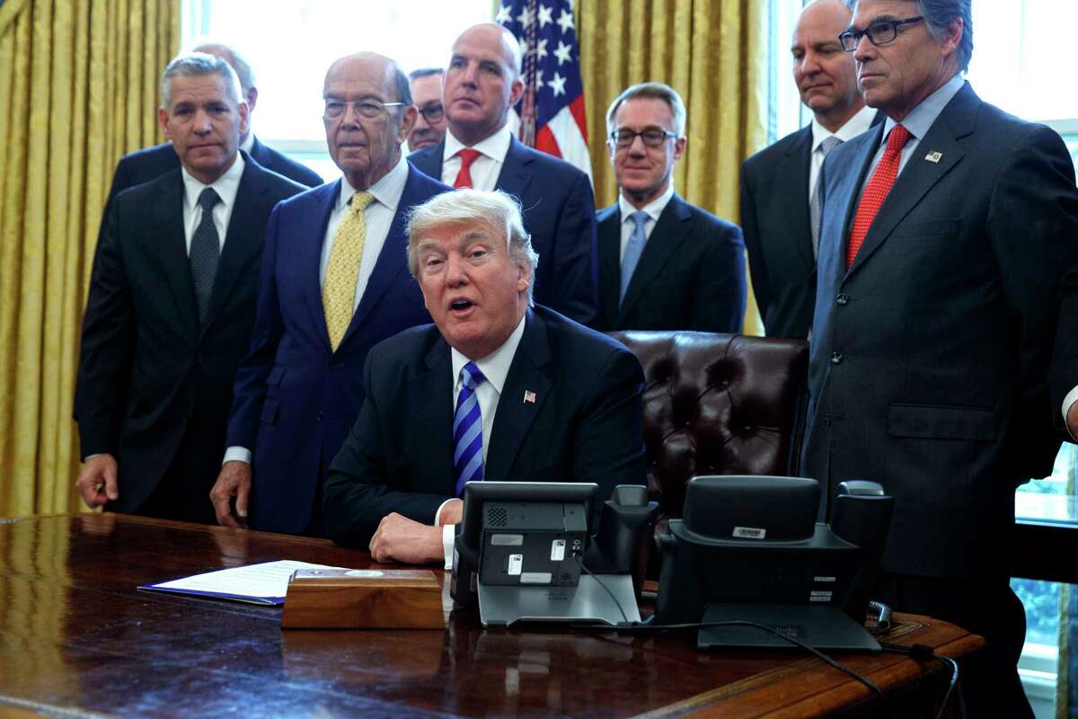 FILE - In this March 24, 2017, file photo, President Donald Trump announces the approval of a permit to build the Keystone XL pipeline, clearing the way for the $8 billion project in the Oval Office of the White House in Washington. From left are, TransCanada CEO Russell K. Girling, Commerce Secretary Wilbur Ross and Energy Secretary Rick Perry. Amid staff turmoil and shake-ups, travel bans blocked by federal courts and the Russia cloud hanging overhead, Trump is plucking away at another piece of his agenda: undoing Obama. (AP Photo/Evan Vucci)