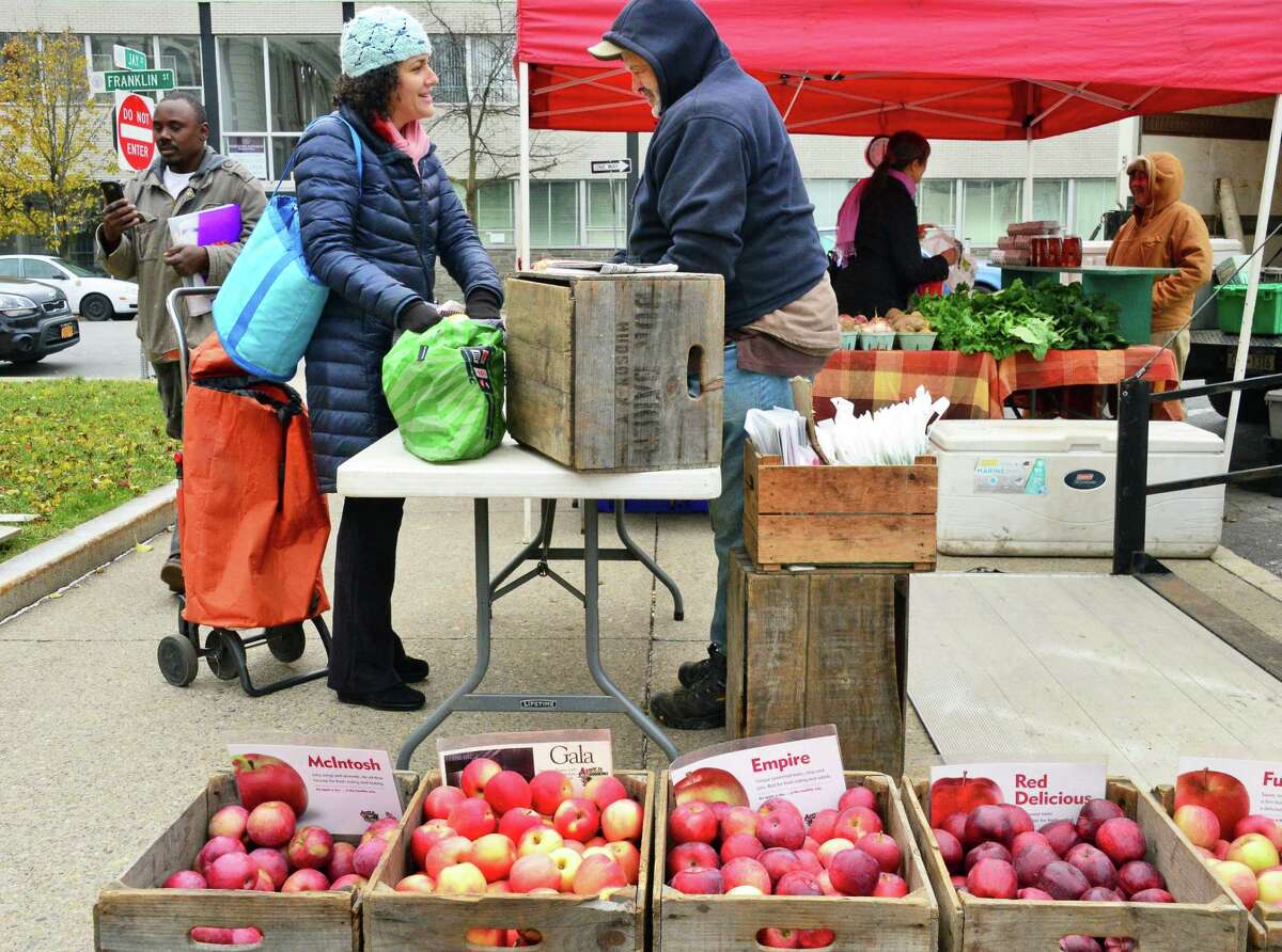 Katie Illouz of Niskayuna, left, buys apples from Dale Baker of Don Baker Farm in Hudson at the Schenectady Farmers Market at City Hall Thursday Dec. 7, 2017 in Schenectady, NY. (John Carl D'Annibale / Times Union)