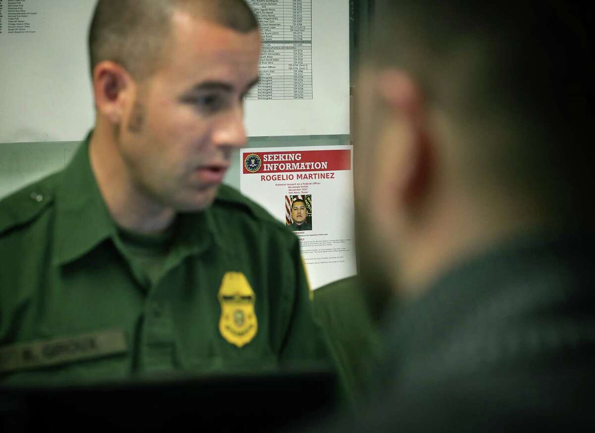 A flyer is seen on the wall about Agent Rogelio Martinez as Border Patrol agent Ben Giroux, left, processes an apprehended undocumented man from Mexico in the Marfa office in the Big Bend Sector, where Martinez worked and died while on patrol. An FBI report says an attack on agents wasn’t the cause. It was likely an accident.