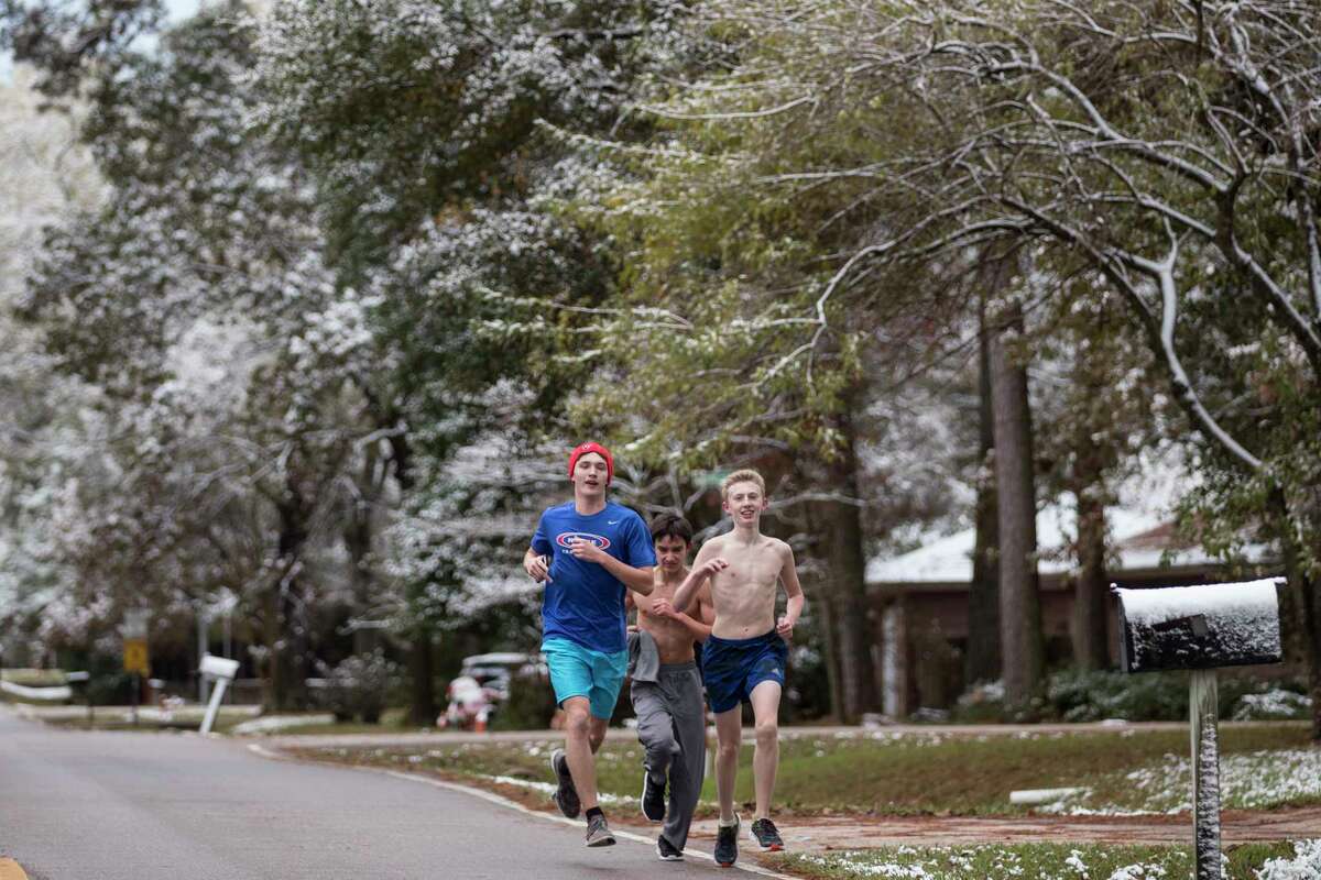 A trio of runners run under snow-covered trees during a workout for the Oak Ridge High School cross country team after the area saw snow fall overnight on Friday, Dec. 8, 2017, in Oak Ridge North, Texas.