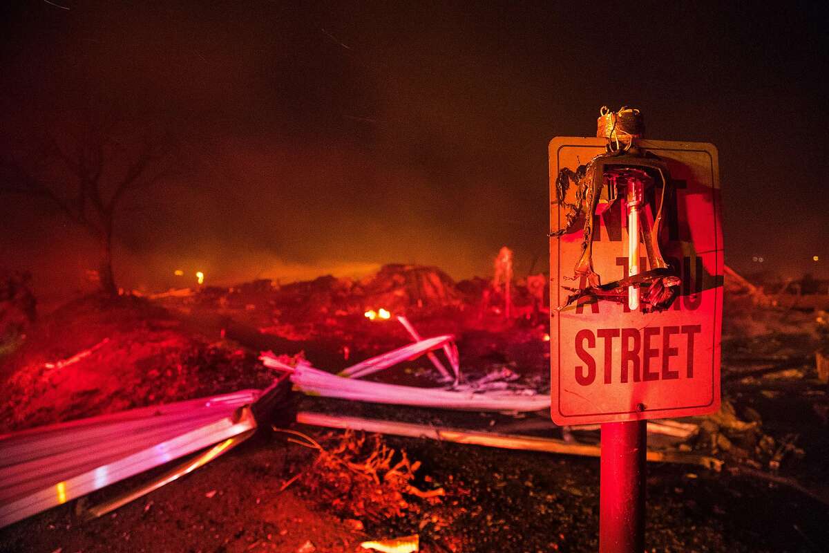 A burned street lamp hangs over a road sign in front of complete devastation after the Lilac fire burned rows and rows of mobile homes at Rancho Monserate Country Club on Dec. 7, 2017 in Pala Mesa, Calif. (Gina Ferazzi /Los Angeles Times/TNS)
