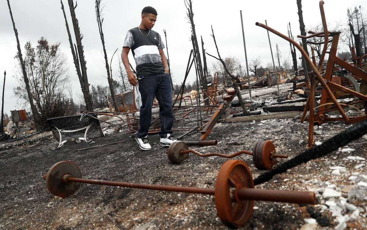 Cardinal Newman football player Nikko Kitchen looks to salvage some of his work out equipment on Friday, November 3, 2017, while visiting his family's house that burned to the ground during the Tubbs' Fire in the Coffey Park subdivision in Santa Rosa, Calif.