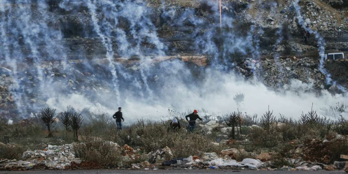 Palestinian protesters run from falling tear gas canisters fired by Israeli forces during clashes near an Israeli checkpoint in the West Bank city of Ramallah on December 10, 2017, following the US president's controversial recognition of Jerusalem as Israel's capital. New protests flared in the Middle East and elsewhere over US President Donald Trump's December 6 declaration of Jerusalem as Israel's capital, a move that has drawn global condemnation and sparked days of unrest in the Palestinian territories.