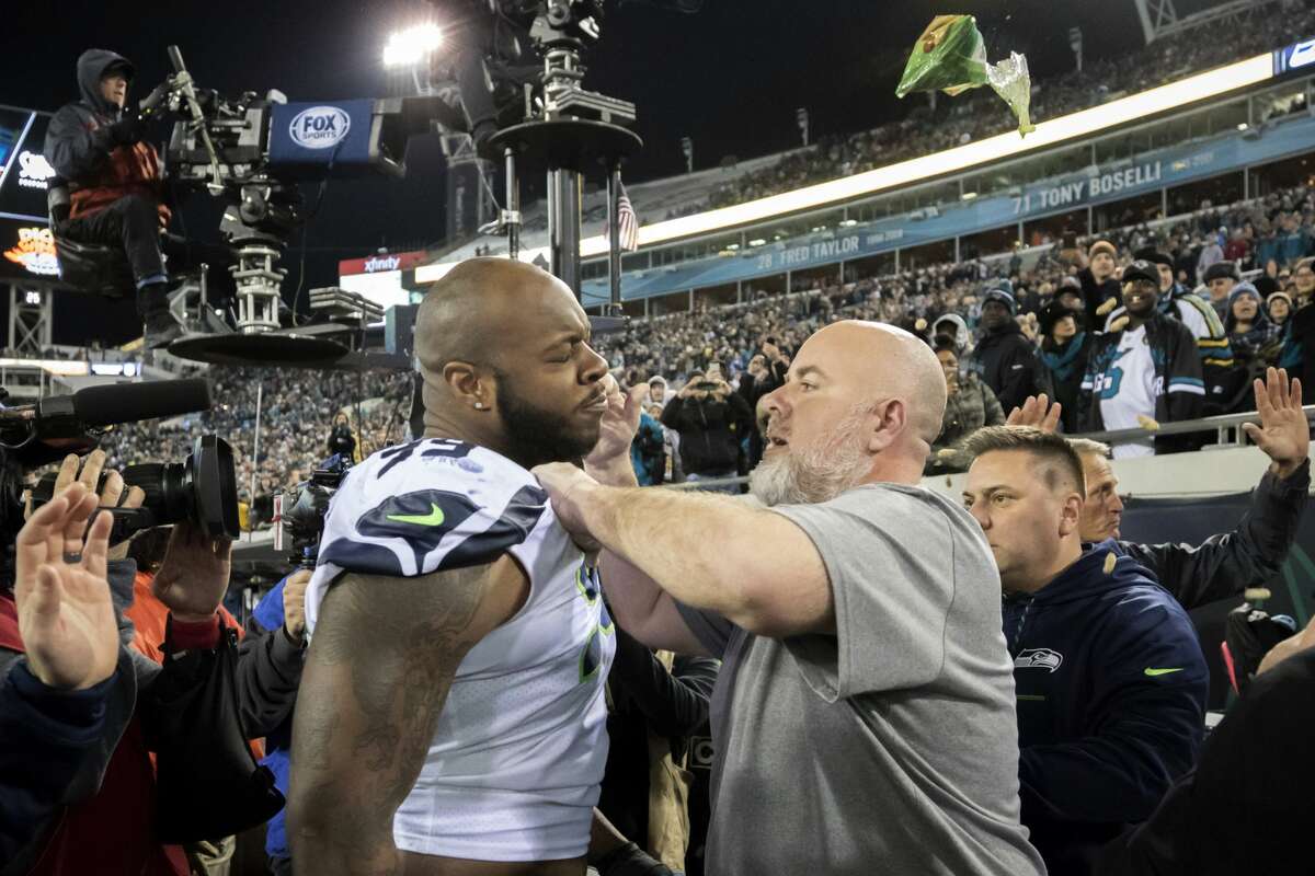 A Seattle Seahawks staff member tries to remove Seahawks defensive tackle Quinton Jefferson, left, from the field as an object thrown from the stands hits them during the closing moments of an NFL football game against the Jacksonville Jaguars, Sunday, Dec. 10, 2017, in Jacksonville, Fla. Jacksonville won 30-24. (AP Photo/Stephen B. Morton)