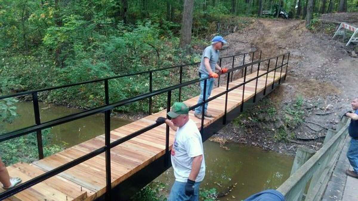 People work on a bridge constructed by Midland Parks and Recreation staff from recycled materials to replace damaged bridges after June flooding. (Photos provided/City of Midland)