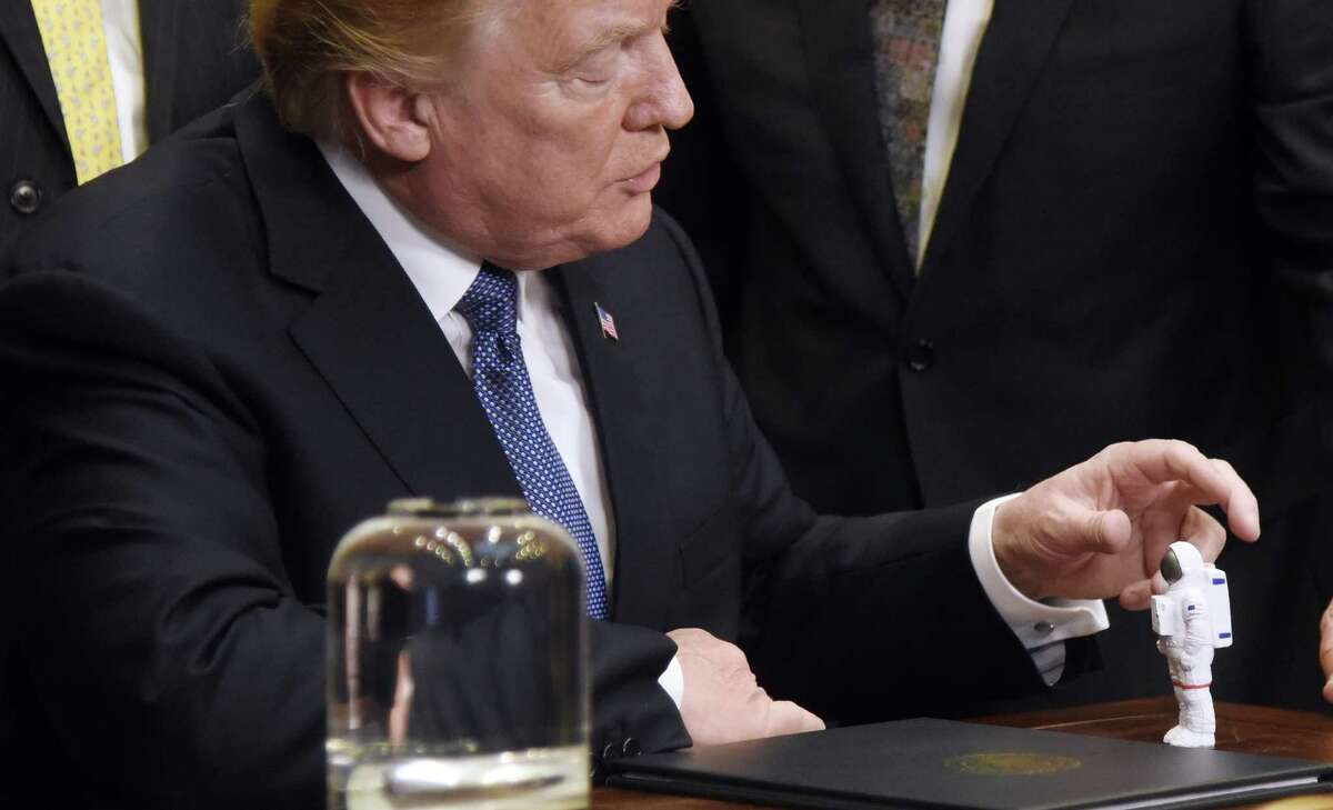 President Donald Trump holds an astronaut figure given by Apollo 17 astronaut Harrison Schmitt Monday during a signing ceremony at the White House reinstating the National Space Council with the goal of sending American astronauts back to deep space. (Olivier Douliery/Abaca Press/TNS)