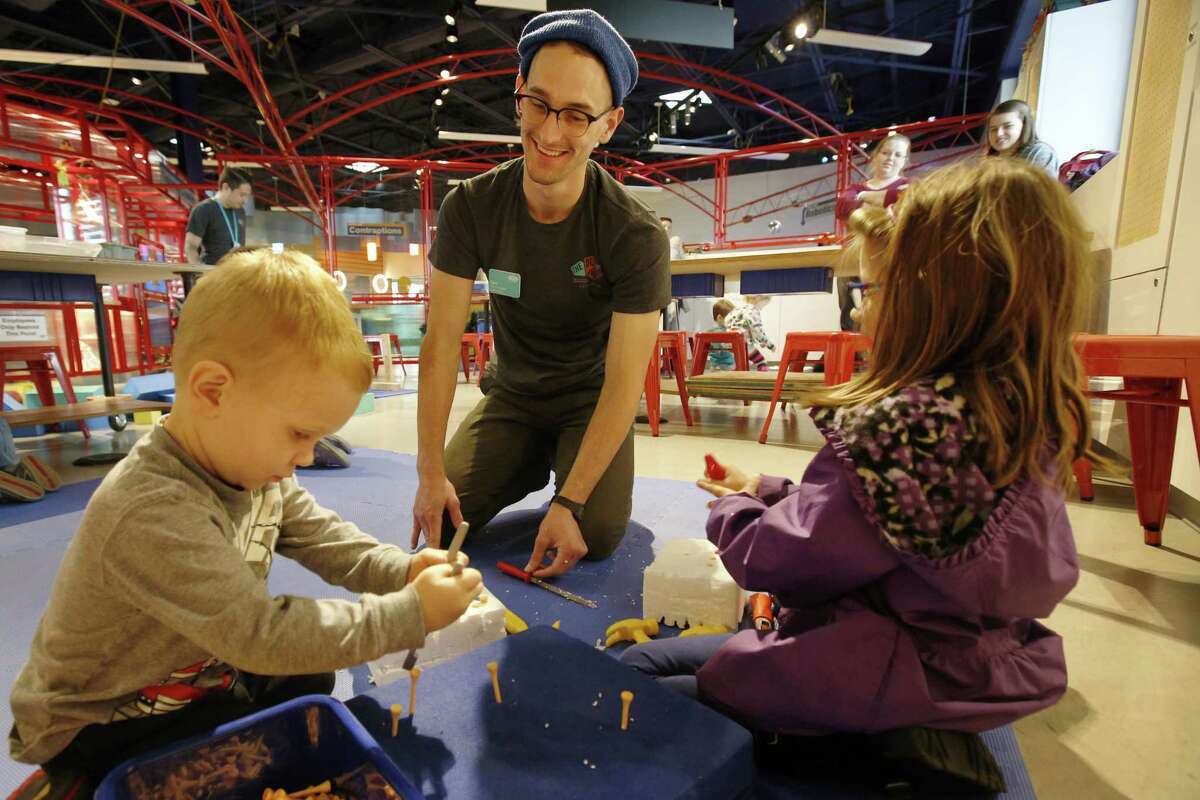 Xavian Calle (from left), 2, DoSeum maker Clint Taylor and Madeleine Lambert, 6, go to work on plastic foam at the DoSeum’s Innovation Station.