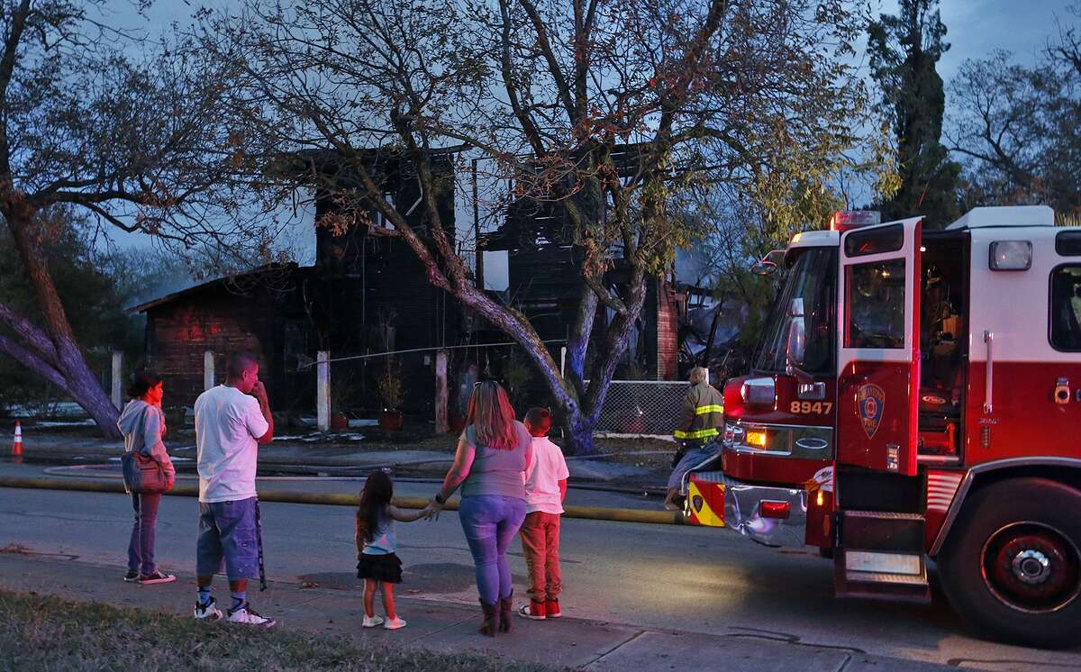 Onlookers watch firefighters extinguish hot spots on a home in the 2100 block of West Travis Street Monday Dec. 11, 2017.