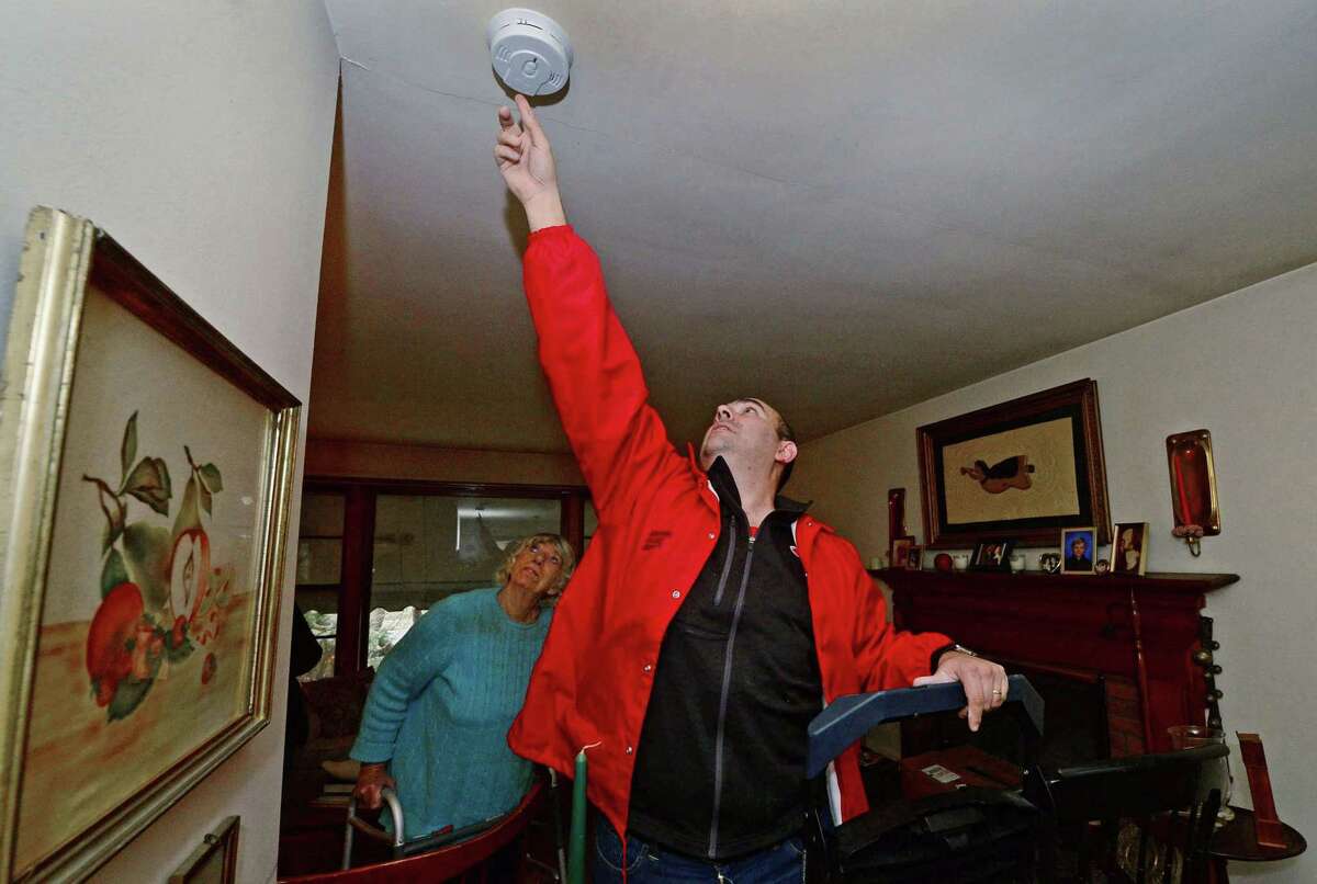 Red Cross of Rhode Island and Connecticut CEO Mario Bruno replaces smoke detectors in the home of Elaine Andersen Tuesday, March 17, 2017, as they visit homes to share fire safety. The crew helped area residents understand the importance of fire safety and help them develop personalized family escape plans to use in the event a fire breaks out in their home.