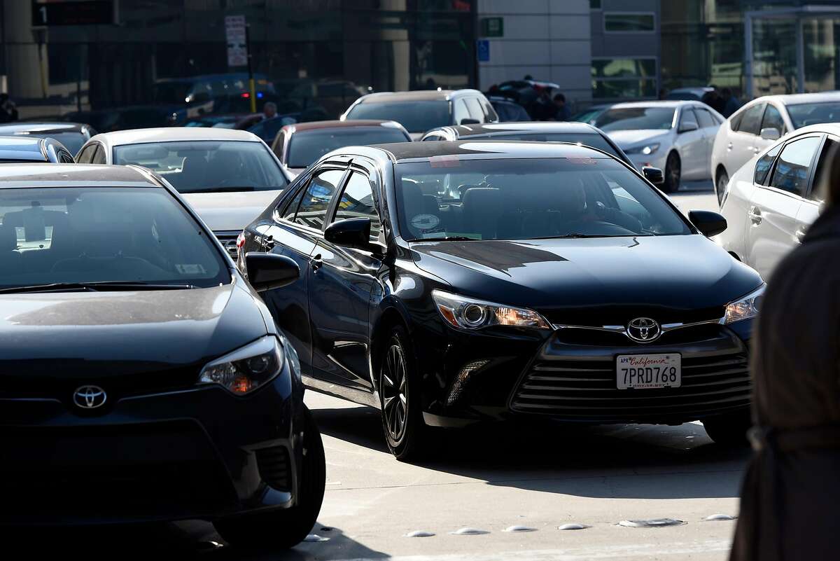 A car with Uber and Lyft tags is seen in the traffic in front of the arrivals terminal at San Francisco International Airport in San Francisco, Calif., on Wednesday December 13, 2017.