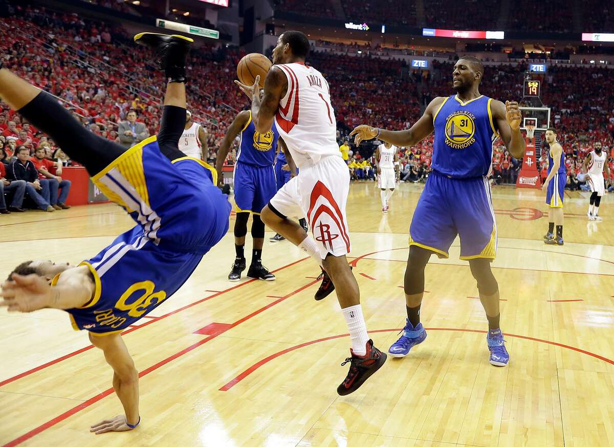 Golden State Warriors guard Stephen Curry (30) topples over Houston Rockets forward Trevor Ariza (1) during the first half in Game 4 of the Western Conference finals of the NBA basketball playoffs as center Festus Ezeli (31) looks on, Monday, May 25, 2015, in Houston. (AP Photo/David J. Phillip)
