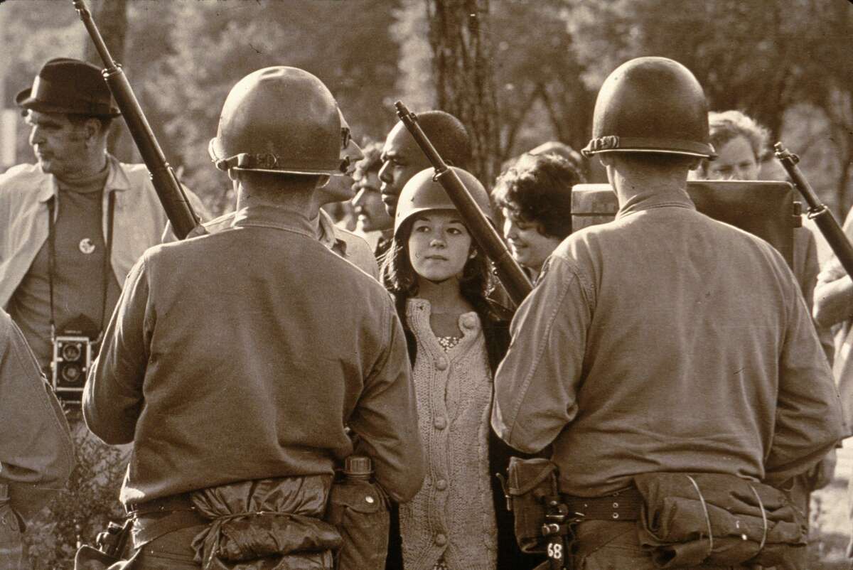A young female protester wearing a helmet faces down helmeted and armed police officers at an anti-Vietnam War demonstration outside the 1968 Democratic National Convention, Chicago, Illinois, August 1968.