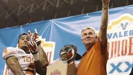 Texas head coach Mack Brown shows the Longhorn sign along with player Kenny Vaccaro (04) after receiving the 20th Valero Alamo Bowl trophy for defeating Oregon State on Dec. 29, 2012. Texas won, 31-27.
