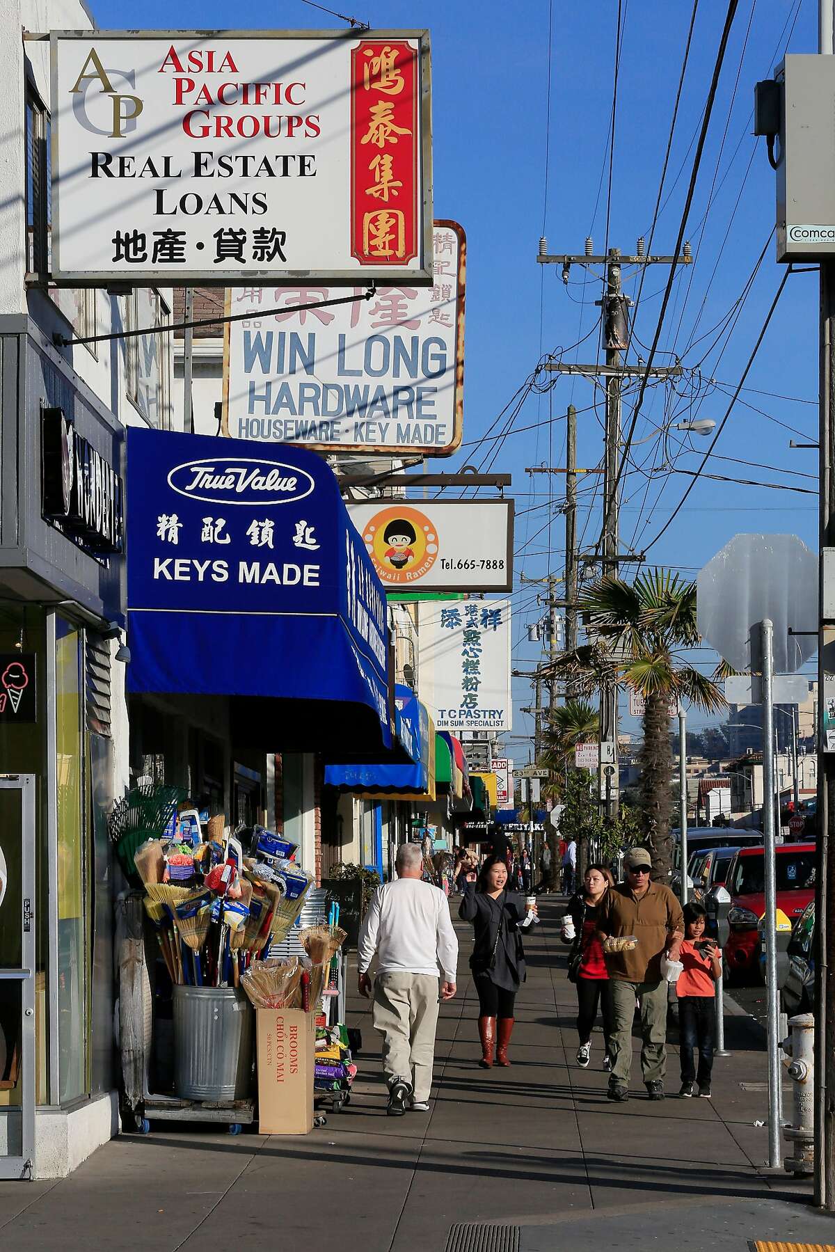 People walk along Irving Street below store signs on Thursday, December 14, 2017 in San Francisco, Calif.