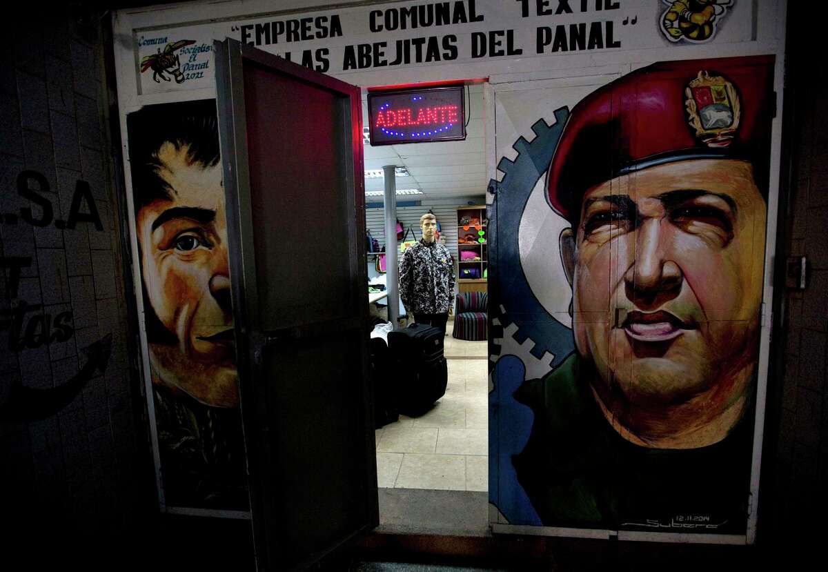 Images of Venezuela's late President Hugo Chavez and independence hero Simon Bolivar blanket the door to a fashion store with a message above it doors that announce to customers hey accept Panales, in the 23 de Enero neighborhood of Caracas, Venezuela, Friday, Dec. 15, 2017. Residents of the neighborhood in cash-strapped Venezuela say theyÂ?’ve found a solution to a lack of paper money by creating the quasi-currency they are calling Panal, that translates from Spanish to honeycomb. (AP Photo/Fernando Llano)