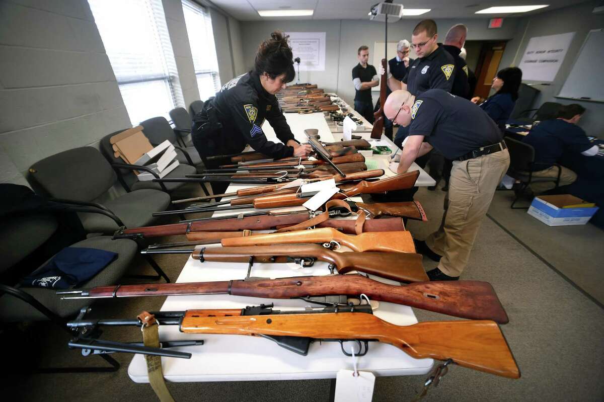 Sgt. Charlette Barham (left) and Detective Josh Kyle (right) catalogue rifles brought in during a gun buy-back at the New Haven Police Academy in New Haven on December 16, 2017.