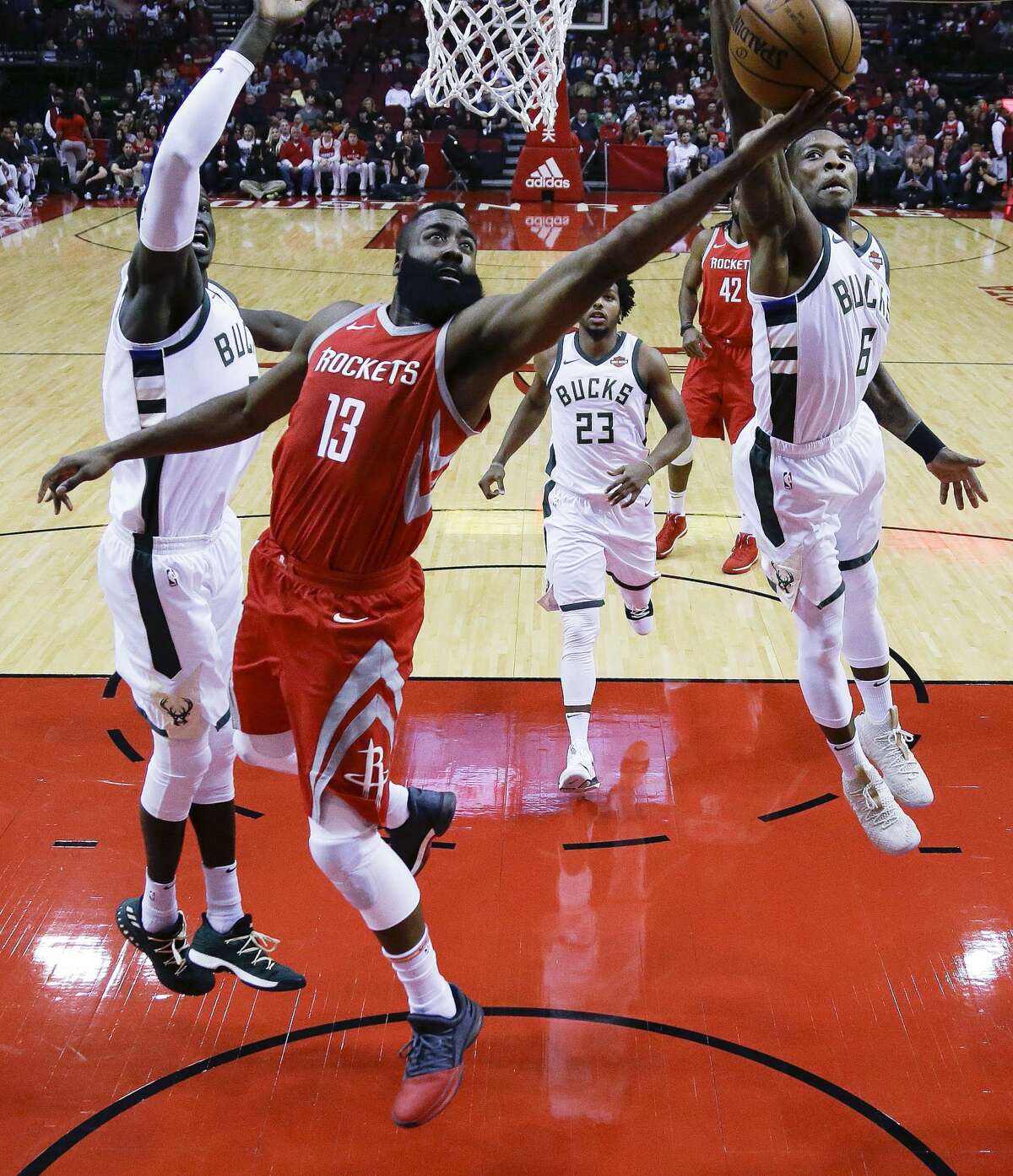 Houston Rockets guard James Harden (13) drives between Milwaukee Bucks center Thon Maker, left, and guard Eric Bledsoe during the first half of an NBA basketball game, Saturday, Dec. 16, 2017, in Houston. (AP Photo/Eric Christian Smith)