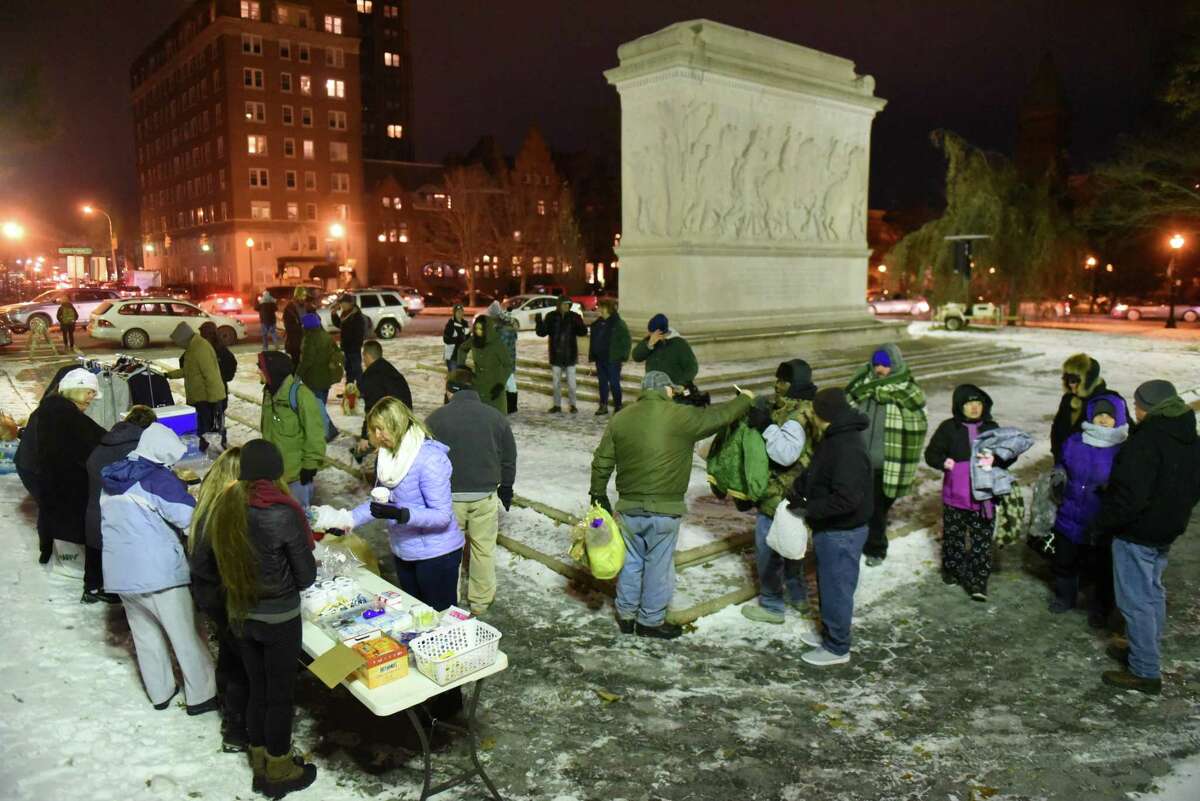 Volunteers and people in need gather in Washington Park where Street Soldiers handed out food, clothing and other necessities to the needy on Friday, Dec. 15, 2017, in Albany, N.Y. Community volunteers, who call themselves street soldiers, gather at the Washington Park memorial every Friday to distribute home-cooked food, clothes and other necessities to homeless people. (Massarah Mikati/Times Union)