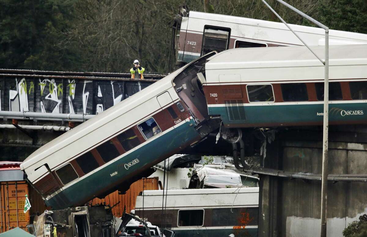 An investigator takes photos off a railroad bridge at the scene of where an Amtrak train derailed above Interstate 5, Monday, Dec. 18, 2017, in DuPont, Wash. The Amtrak train making the first-ever run along a faster new route hurtled off the overpass Monday near Tacoma and spilled some of its cars onto the highway below, killing several people, authorities said. (AP Photo/Elaine Thompson)
