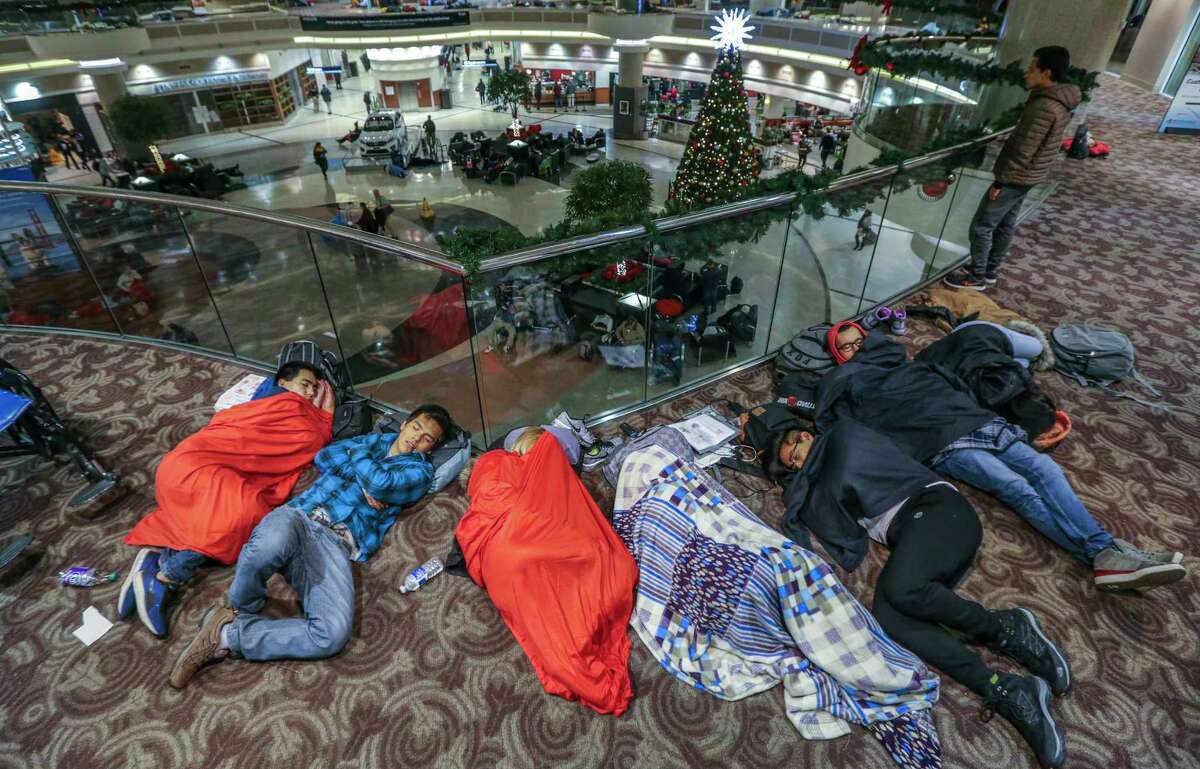 Travelers sleep in the atrium at Hartsfield-Jackson International Airport on Monday, Dec. 18, 2017, the day after a massive power outage brought operations to halt. Power was restored at the world's busiest airport after a massive outage Sunday afternoon that left planes and passengers stranded for hours, forced airlines to cancel more than 1,100 flights and created a logistical nightmare during the already-busy holiday travel season. (John Spink/Atlanta Journal-Constitution via AP) ORG XMIT: GAATJ103
