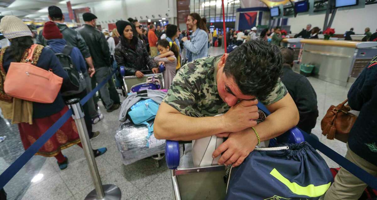 Alexis Canete rests on his luggage as he waits in the Delta ticket line to get back home to Cuba from his visit to Tennessee on Monday Dec. 18, 2017 at Hartsfield-Jackson International Airport in Atlanta, the day after a massive power outage brought operations to halt. Power was restored at the world's busiest airport after a massive outage Sunday afternoon that left planes and passengers stranded for hours, forced airlines to cancel more than 1,100 flights and created a logistical nightmare during the already-busy holiday travel season. (John Spink/Atlanta Journal-Constitution via AP) ORG XMIT: GAATJ101