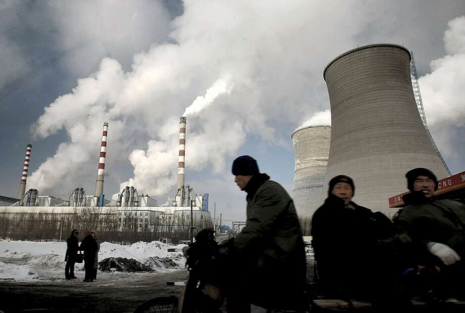 In this file photo, workers cycle past a coal-fired power plant on a tricycle cart in Changchun, in northeast China's Jilin province. Carbon dioxide concentrations - whose "greenhouse gas effect" traps heat
 and drives climate change - were around 280 parts per million circa 
1880, at the dawn of the industrial revolution. They're now 46 percent 
higher. Photo: ASSOCIATED PRESS