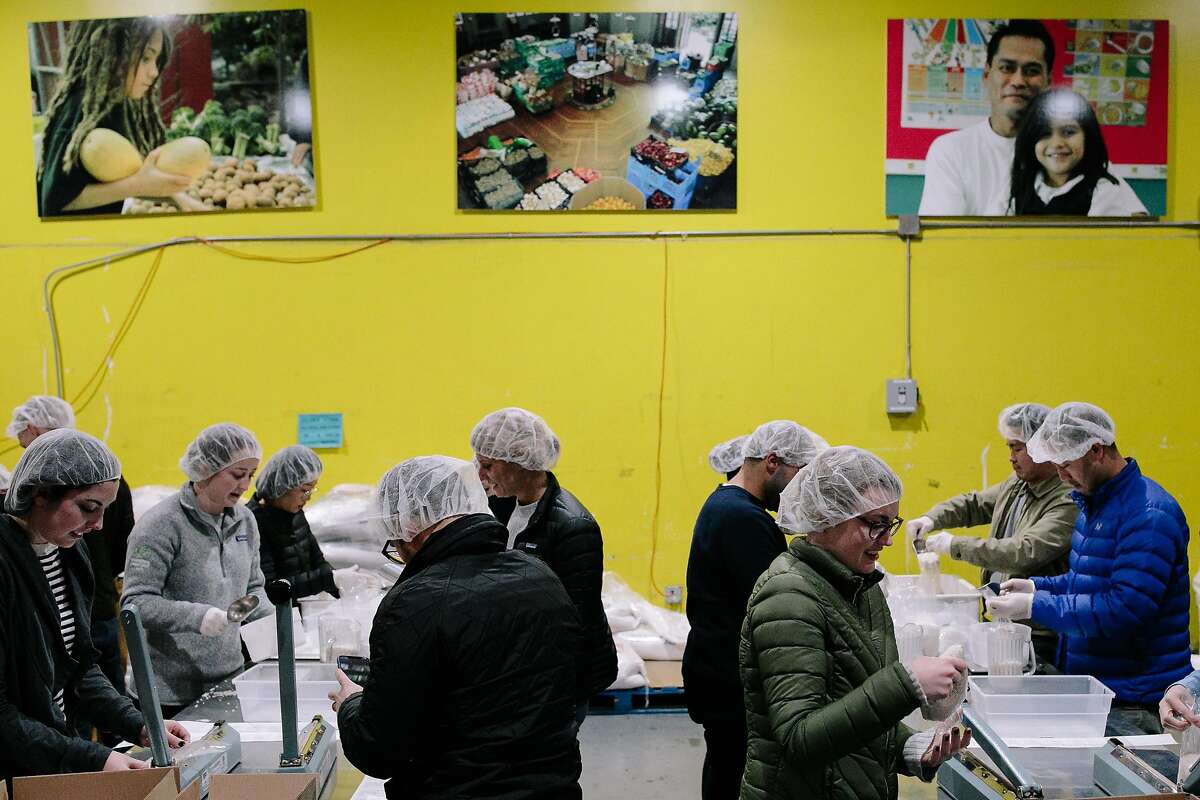 Volunteers package rice at the SF-Marin Food Bank in San Francisco, Calif. Monday, December 18, 2017.