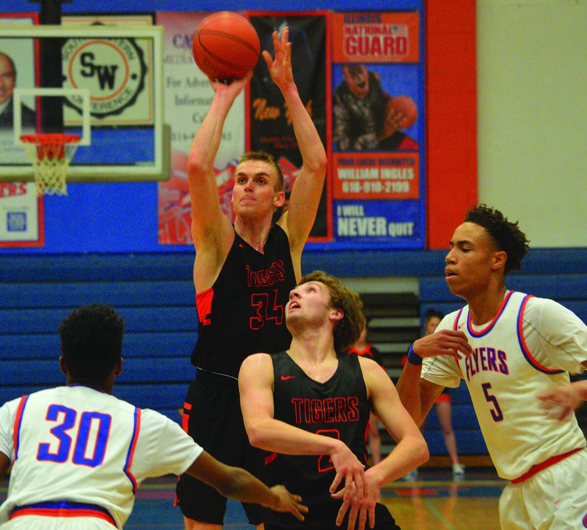 Edwardsville senior forward Caleb Strohmeier (No. 34) puts up a shot over teammate Jack Marinko and two East St. Louis defenders during Wednesday’s Southwestern Conference game in East St. Louis.