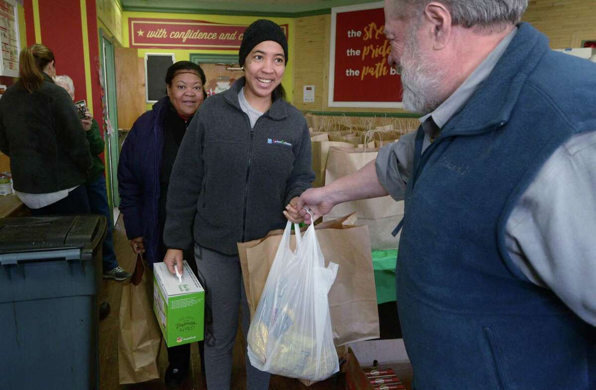 Volunteers from the First Congregational Church in Darien including Dave Miller, help distribute holiday dinner baskets to over 100 local individuals and their families like Dinorca Guerrero, center, during the Open Door Shelter’s annual program Thursday, in Norwalk.