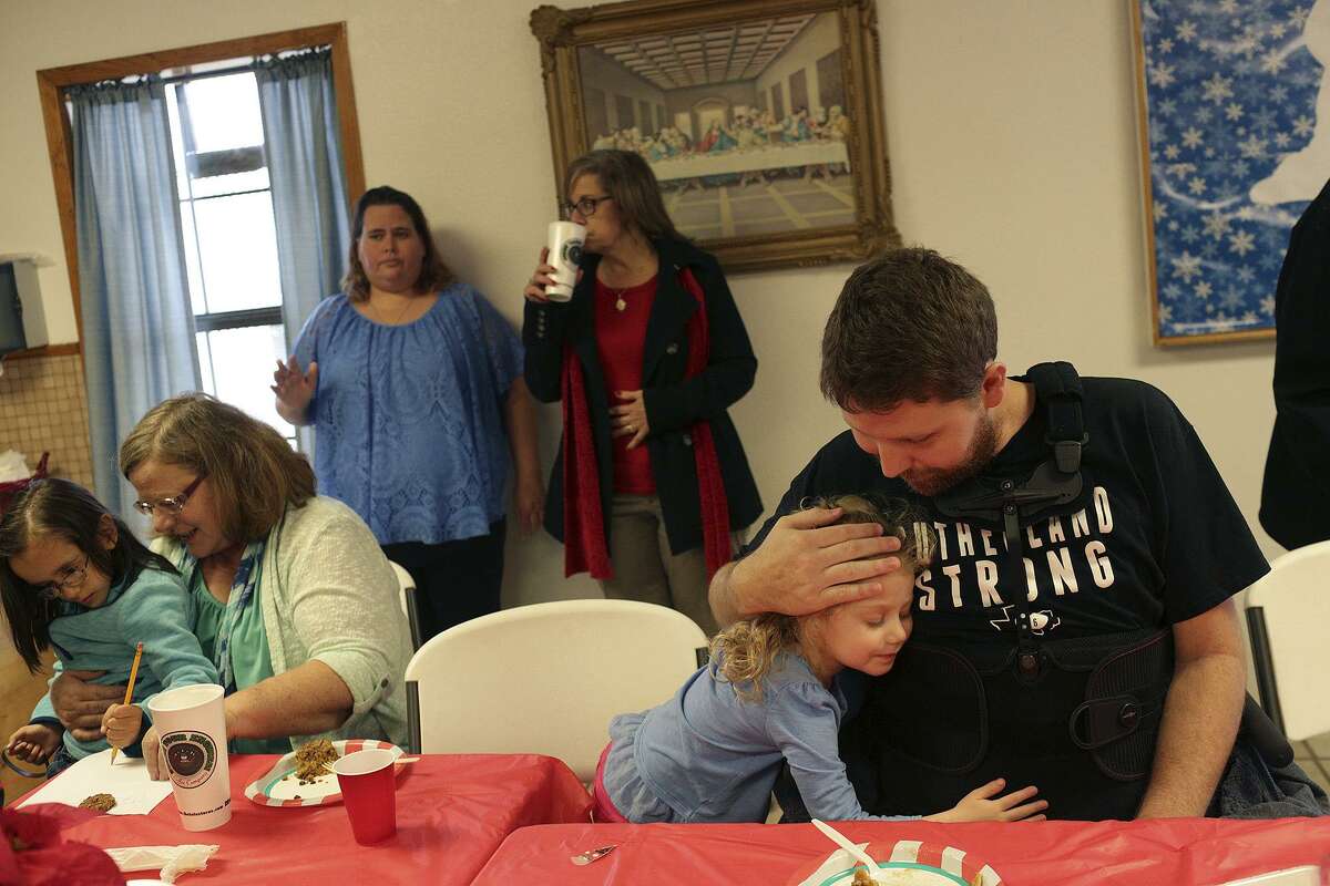 Kris Workman holds his daughter, Eevee Workman, 3, at the First Baptist Church Christmas Potluck in Sutherland Springs on Sunday, Dec. 17, 2017. Sunday was Workman's first visit back to the church since he was shot in the back and paralyzed from the waist down on Nov. 5. At left is Stormy Choate with Yazmeen Briggs, 5.