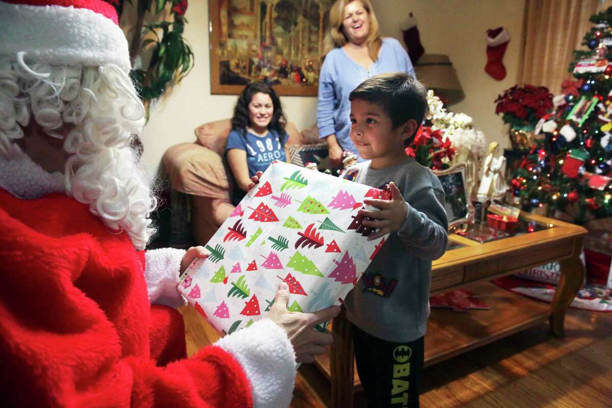 In this 2017 photo, a child receives a present from Santa through the the Elf Louise Christmas Project. As a child, Louise Locker, the program’s founder, would tell her mother, “Can you imagine if everybody knew the potential for goodness inside of them and they acted upon it, how different the world will be?”