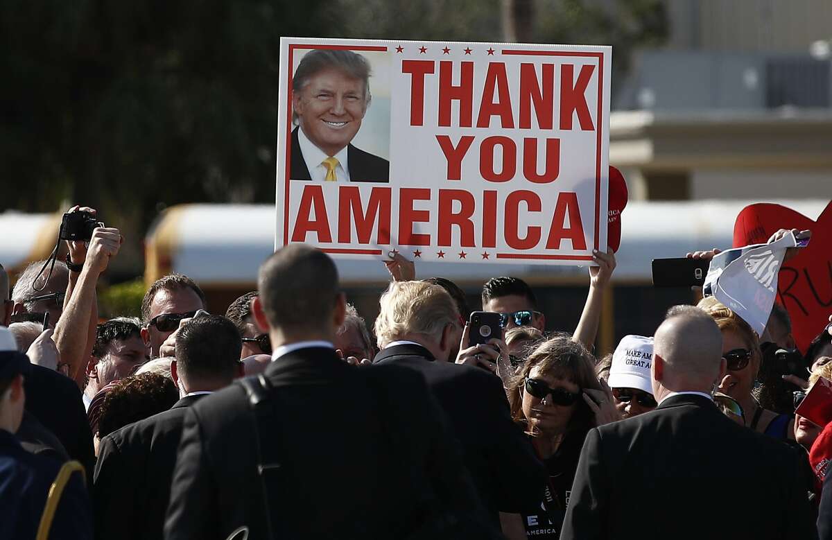 President Donald Trump greets people on the tarmac as he arrives on Air Force One at Palm Beach International Airport, in West Palm Beach, Fla., Friday, Dec. 22, 2017. (AP Photo/Carolyn Kaster)