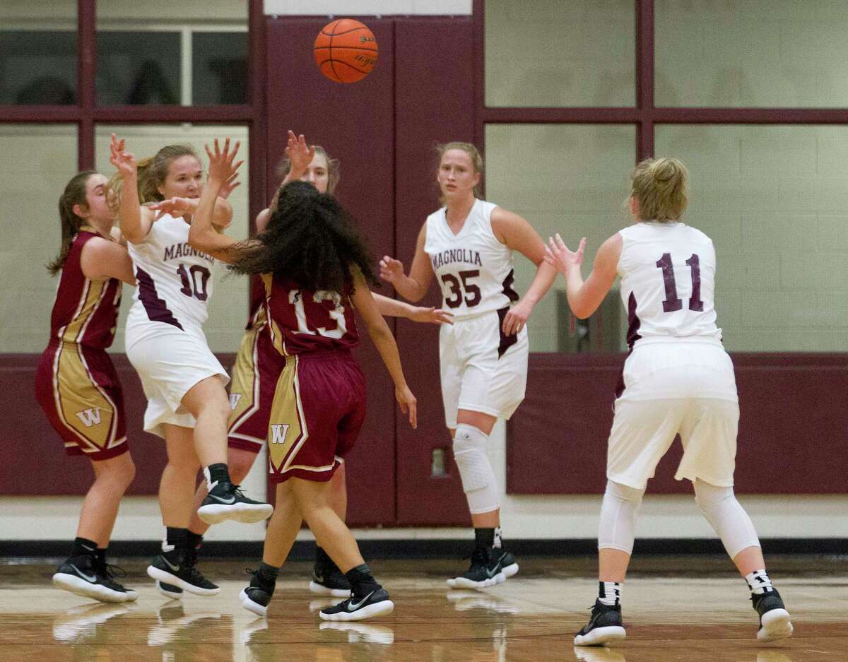 Magnolia guard Lexi Bearden (10) makes a pass under pressure to forward Caroline Hittler (11) during the second quarter of a District 20-5A high school girls basketball game at Magnolia High School, Friday, Dec. 22, 2017, in Magnolia.