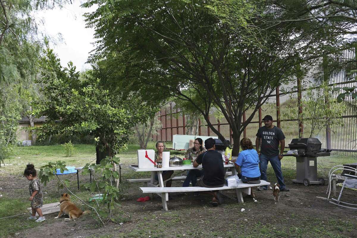 In La Lomita neighborhood of Brownsville, Texas, the Granados family grills in their backyard in October 2016. The neighborhood is next to the U.S.-Mexico border wall and serves as a backdrop to the family's Dallas Cowboys game-watch cookouts.