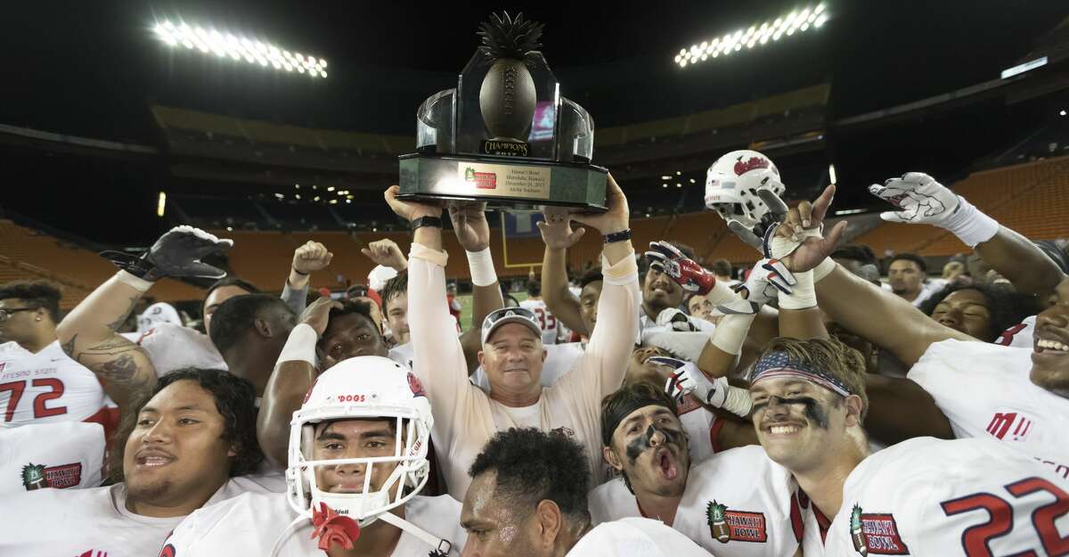 Fresno State head coach Jeff Tedford, center, holds up the Hawaii Bowl championship trophy after defeating Houston in the Hawaii Bowl NCAA college football game, Sunday, Dec. 24, 2017, in Honolulu. Fresno State won, 33-27. (AP Photo/Eugene Tanner)