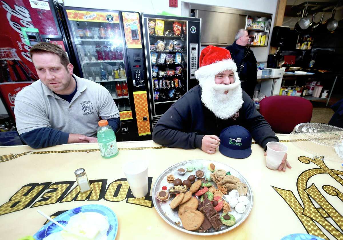 Firefighter Mark Misbach, right, dons a Santa Claus hat and beard during lunch at the New Haven Fire Department Headquarters on Christmas Day. At left is Lt. Patrick Grant.