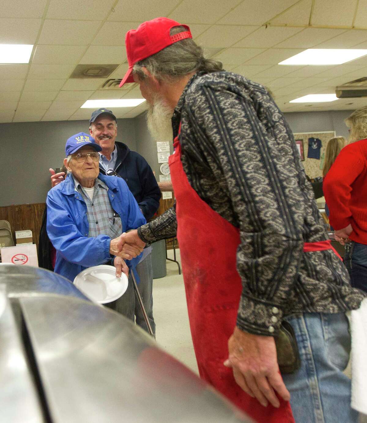 Duane Scott, a World War II veteran who served in the Philippines, shakes hands with U.S. Navy veteran James "Boogie" Fesmire during the annual Conroe Veterans of Foreign War Post 4709 Christmas Day lunch, Monday, Dec. 25, 2017, in Conroe
