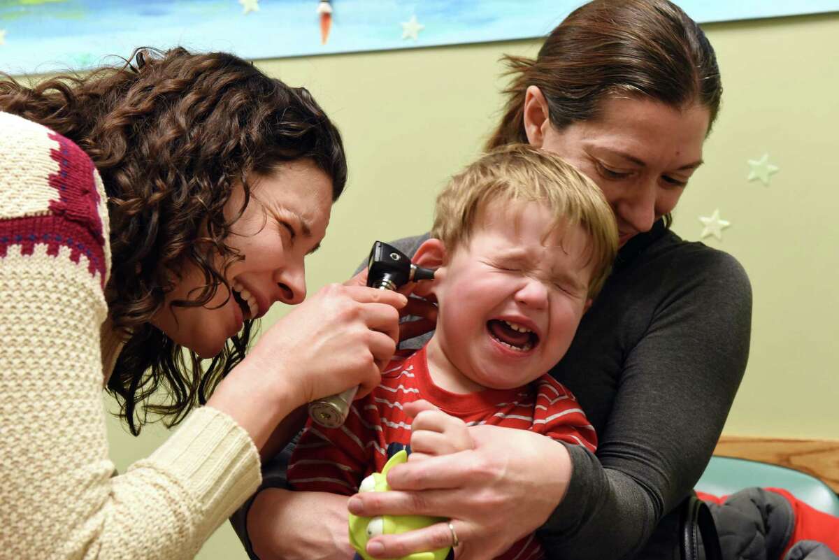Jacob Andrascik, 2, of Guilderland is held by his mother, Valerie, right, as pediatric nurse practitioner, Brooke Raveendranath, left, takes a look in his ear during a medial exam at CapitalCare Pediatrics on Thursday afternoon, Feb. 9, 2017, in Guilderland, N.Y. (Will Waldron/Times Union)