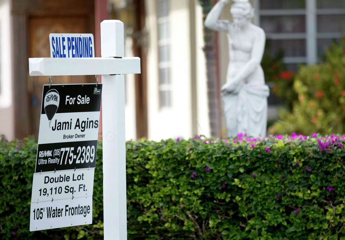 FILE - In this Thursday, Jan. 8, 2015, file photo, a "Sale Pending" placard is placed atop a realty sign outside a home for sale in Surfside, Fla. On Wednesday, Dec. 27, 2017, the National Association of Realtors releases its November report on pending home sales, which are seen as a barometer of future purchases. (AP Photo/Wilfredo Lee, File)
