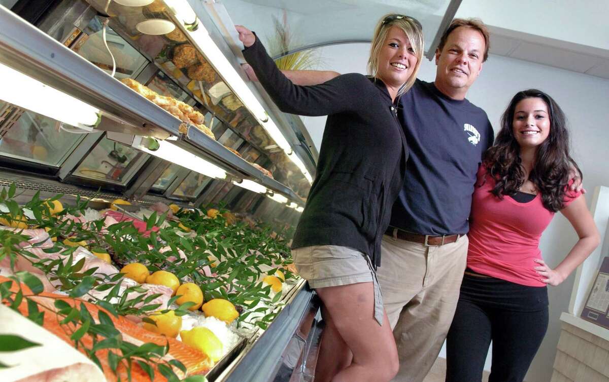 Gary Swanson and his daughters Lynette, left, and Larissa pose in front of the display case at Swanson's Fish Market in Fairfield in 2010. The family-owned business will be closing for good on New Years Eve.