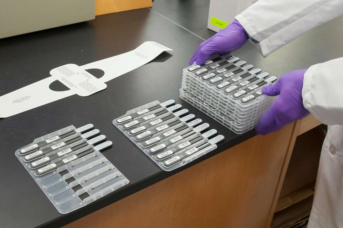 A criminalist with the California Department of Justice Bureau of Forensic Services stacks DNA collectors at the State DNA Laboratory in Richmond.