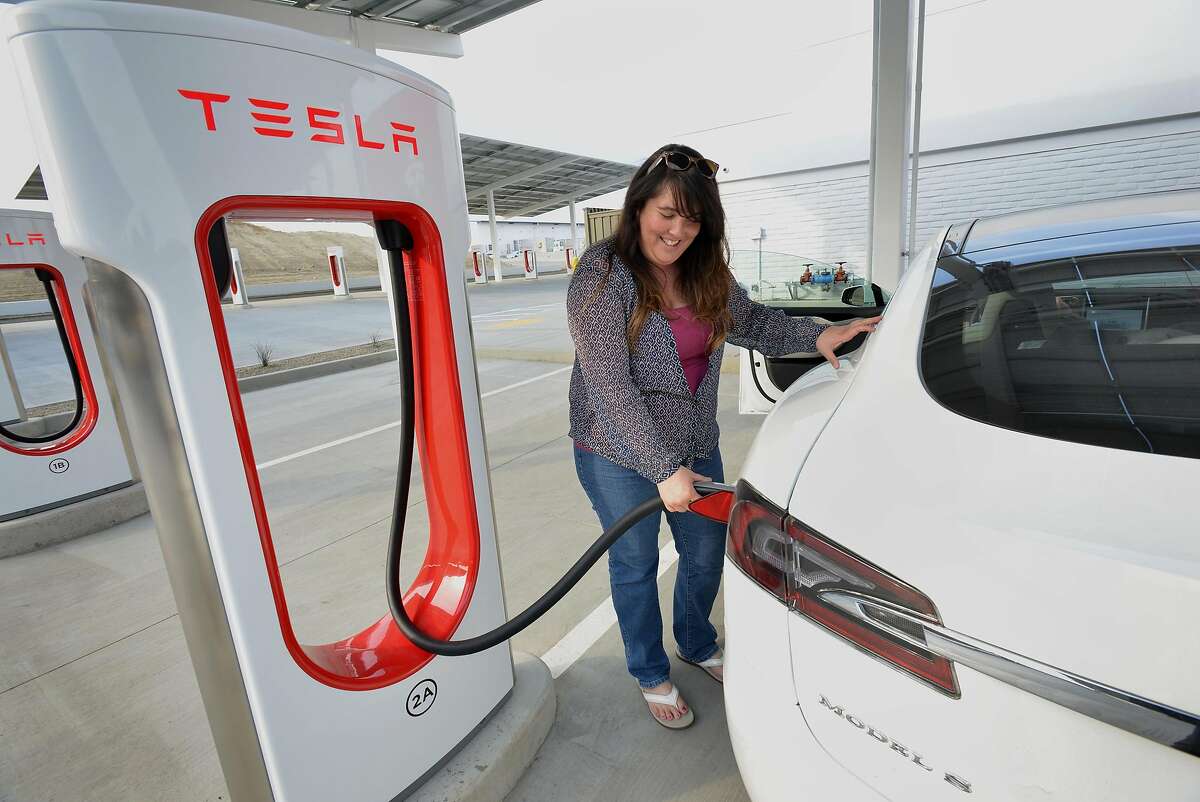 Carolyn Lowe of Fairfield plugs a charger into her sister’s Tesla during a stop for lunch on their way home from Beverly Hills, at the Tesla Supercharger station along I-5 in Kettleman City. 